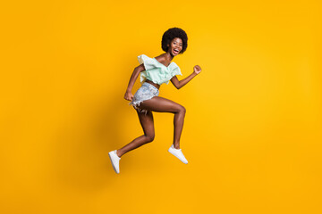Fototapeta na wymiar Full length body size side profile photo of jumping high girl running fast sale laughing isolated on vibrant yellow color background