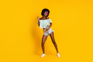 Fototapeta na wymiar Full length body size photo of black skinned woman dancing on weekend wearing star shaped sunglass isolated on vibrant yellow color background