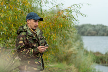 A man holds a smartphone in his hand. A man's conceived look. Military man with a smartphone.