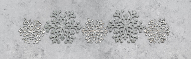 Christmas border. Silvery snowflakes on gray grunge concrete background, banner. Top view, flat lay.