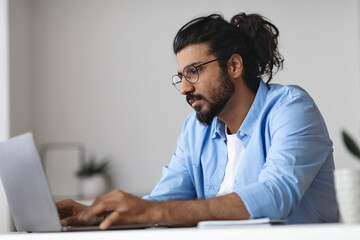 Young Western Employee Working On Laptop At Desk In Office