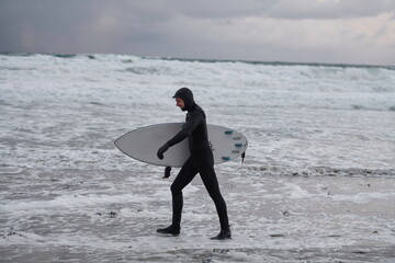 Arctic surfer going by beach after surfing
