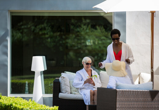 Senior women friends relaxing in spa bathrobes on luxury patio