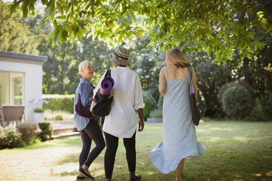 Happy senior women friends with yoga mat in summer garden