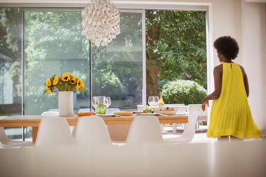 Woman in yellow dress setting dining table for lunch