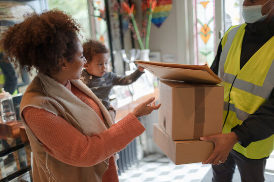 Mother and baby daughter receiving packages from delivery person