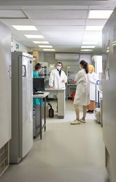 Scientists in face masks meeting in laboratory