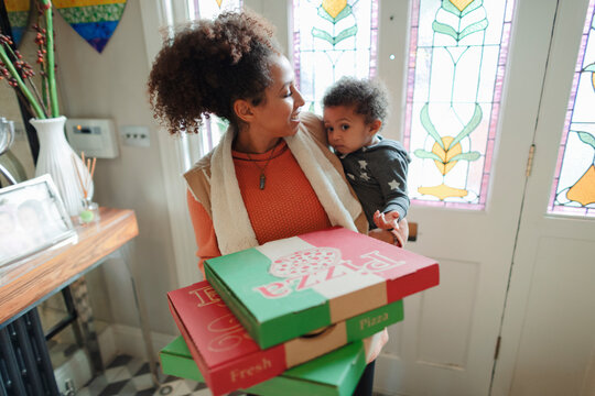 Mother with baby daughter receiving pizza delivery at front door