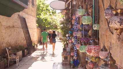 Fototapeta premium Turkish bazaar lamps hanging on the wall. Tourists walking on the street of old town Kaleici, Antalya, Turkey.