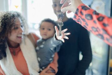 Happy young family receiving new house keys from realtor
