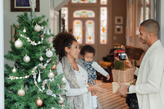 Happy family with Christmas gifts by tree in living room