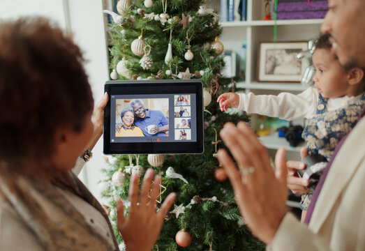 Family video chatting with digital tablet by Christmas tree