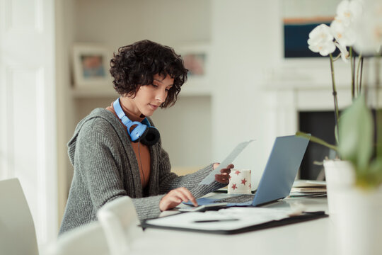 Woman working from home at laptop on dining table