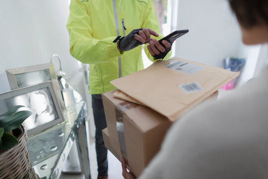 Woman receiving packages from delivery man with smart phone