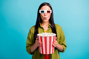 Photo of shocked girl hold big paper bucket popcorn open mouth wear 3d glasses green shirt isolated blue color background