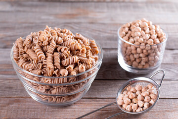 Dried chickpeas and whole wheat pasta in a bowl on the table. Healthy produc