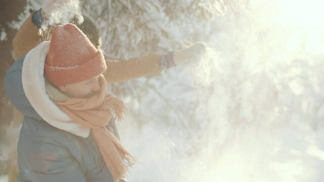 Young male and female friends in outerwear throwing snow at each other while playing together outdoor in forest on winter day