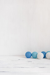 Minimalist home decor. Blue balls garland on a white wooden table, shabby backdrop. Minimal still life. Christmas concept.