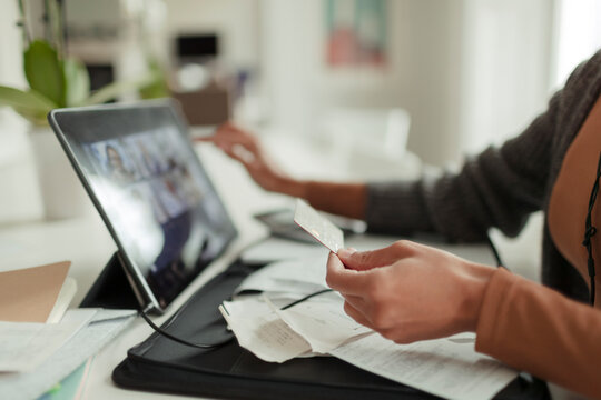 Close up woman with credit card paying bills at digital tablet