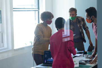 Diverse group of work colleagues wearing masks in an office