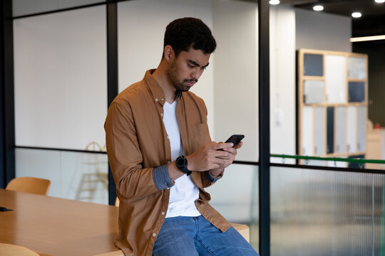 Mixed race businessman texting on smartphone in creative office