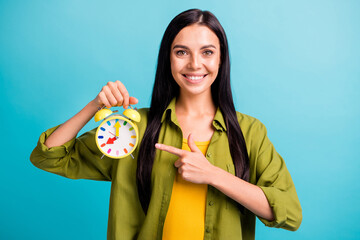 Fototapeta premium Photo of lady hold alarm clock indicate forefinger shiny smile wear green shirt isolated blue color background
