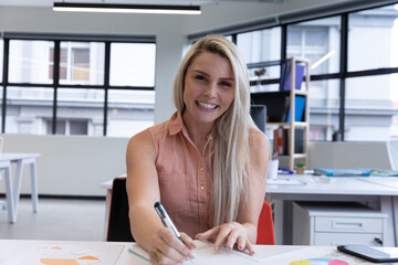 Portrait of smiling caucasian blonde woman working in modern office