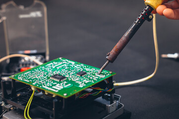 Technician repair electronic circuit board with soldering iron and tin wire.  Repair of electronic...