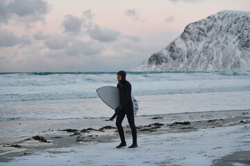 Arctic surfer going by beach after surfing