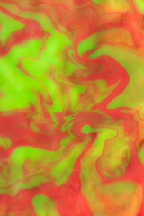 Blurred background of mixed colors of fluorescent orange and yellow shades. Marble pattern mixed paints abstract background