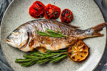  Baked dorado fish on a plate with vegetables top view