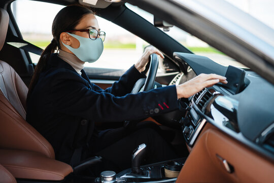 Focused businesswoman in face mask using navigator while driving car