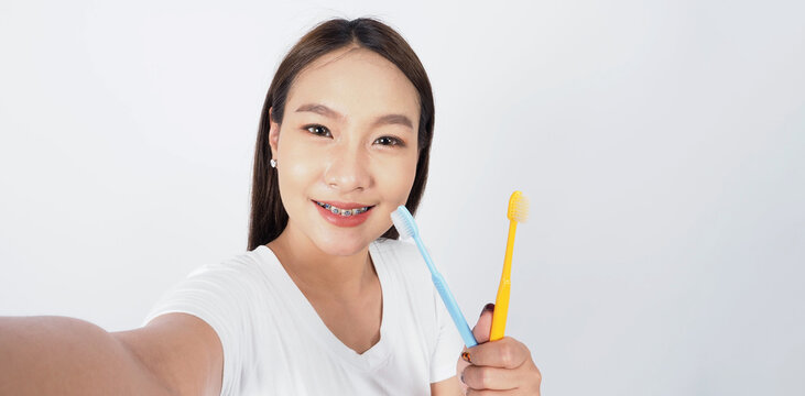 Asian teen facial with braces and toothbrush smiling to camera to show dental orthodonic teeth which include professional metal wire material from orthodontist. studio shot white background. Dental br