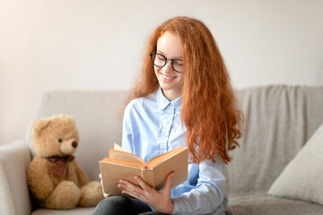 Girl wearing glasses, sitting on the couch, reading book