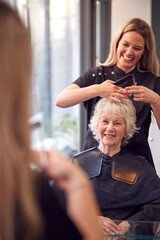 Senior Woman Having Hair Cut By Female Stylist In Hairdressing Salon