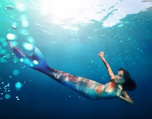Portrait of a girl mermaid with tail swim under water in the ocean