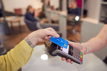 Close Up Of Senior Woman Making Contactless Payment To Stylist In Salon With Credit Card