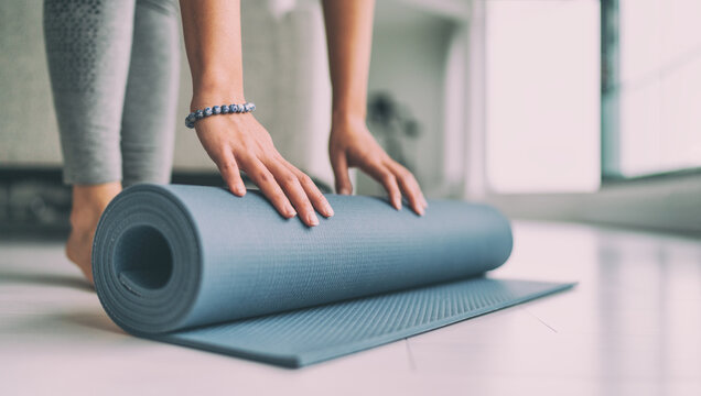 Yoga at home active lifestyle woman rolling exercise mat in living room for morning meditation yoga banner background.