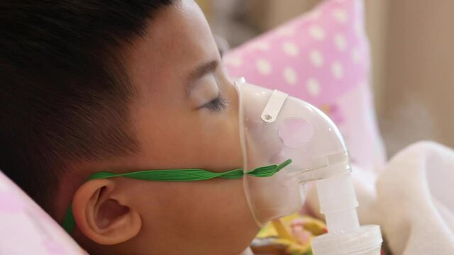 Asian little boy making inhalation with nebulizer at hospital, Nebulization concept