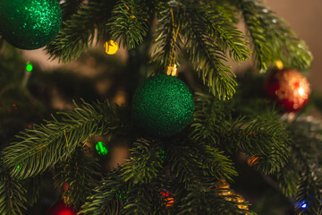 Beautiful Christmas tree with green toy on branches close up. Concept of a New year atmosphere and festive mood