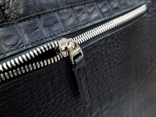 Silver-tone zip fastener on a black leather bag