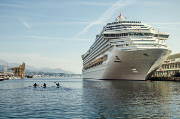 Small canoe boats and big passenger ship in the port of Savona, Italy