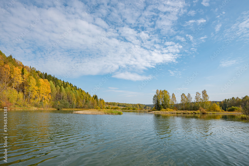 Wall mural autumn forest trees are reflected in the river water of the panoramic landscape. blue sky with cloud