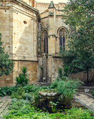 Fototapeta na wymiar Small garden with fountain in the courtyard of the cathedral in Tarragona, Spain
