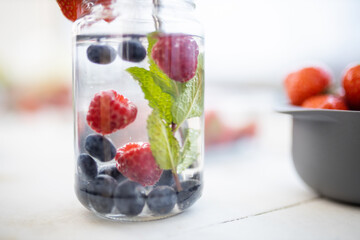Raspberries, blueberries, and mint drink inside a jar