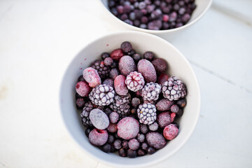Bowls of dark berries on a white kitchen counter