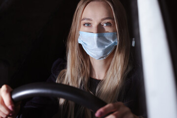 Young woman in a protective mask driving a car