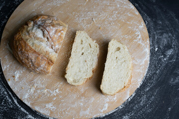 Traditional wheat bread slices with flour on wooden table.Concept of baking, cooking isolated on black background.