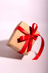 A gift in a kraft paper with red ribbon on a white background