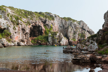 Small beach with turquoise water surrounded by cliffs. Cales Coves, Menorca.